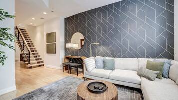 Ein modernes Wohnzimmer mit Treppe, einer Couch, einem Couchtisch und einer Wand mit geometrischem Muster.