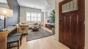 A modern living room with a sofa, coffee table, and a wooden desk with a lamp. - Big and Beautiful 5BR Triplex in Shaw/Bloomingdale (Washington)