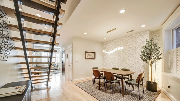 A modern interior with a wooden staircase, a dining area with a table and chairs, and a patterned wall. - Big and Beautiful 5BR Triplex in Shaw/Bloomingdale (Washington)