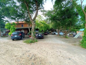 Uma área de estacionamento com carros, árvores e um edifício com telhado vermelho.