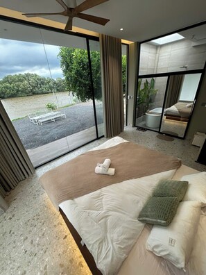 Quarto com uma cama grande, vista para um jardim e banheiro com banheira.