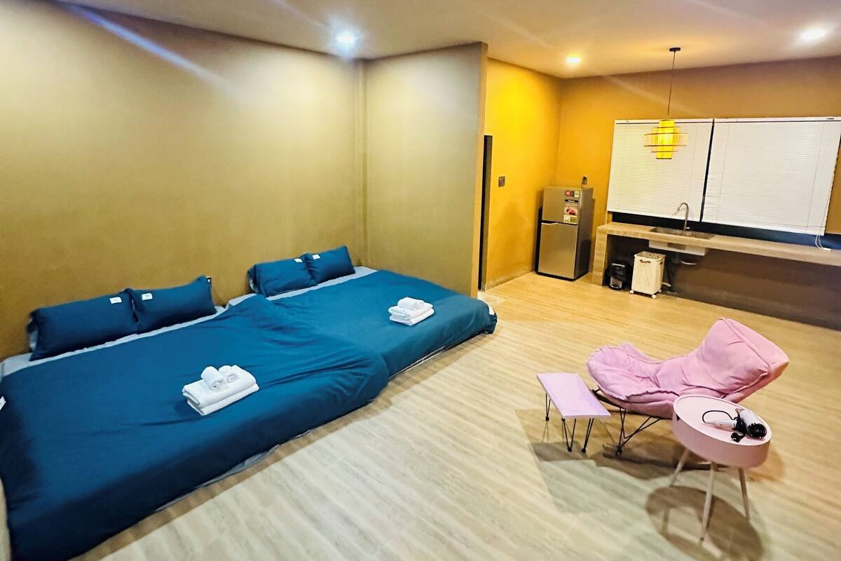 A hotel room with a large bed, a desk, a chair, and a minibar.