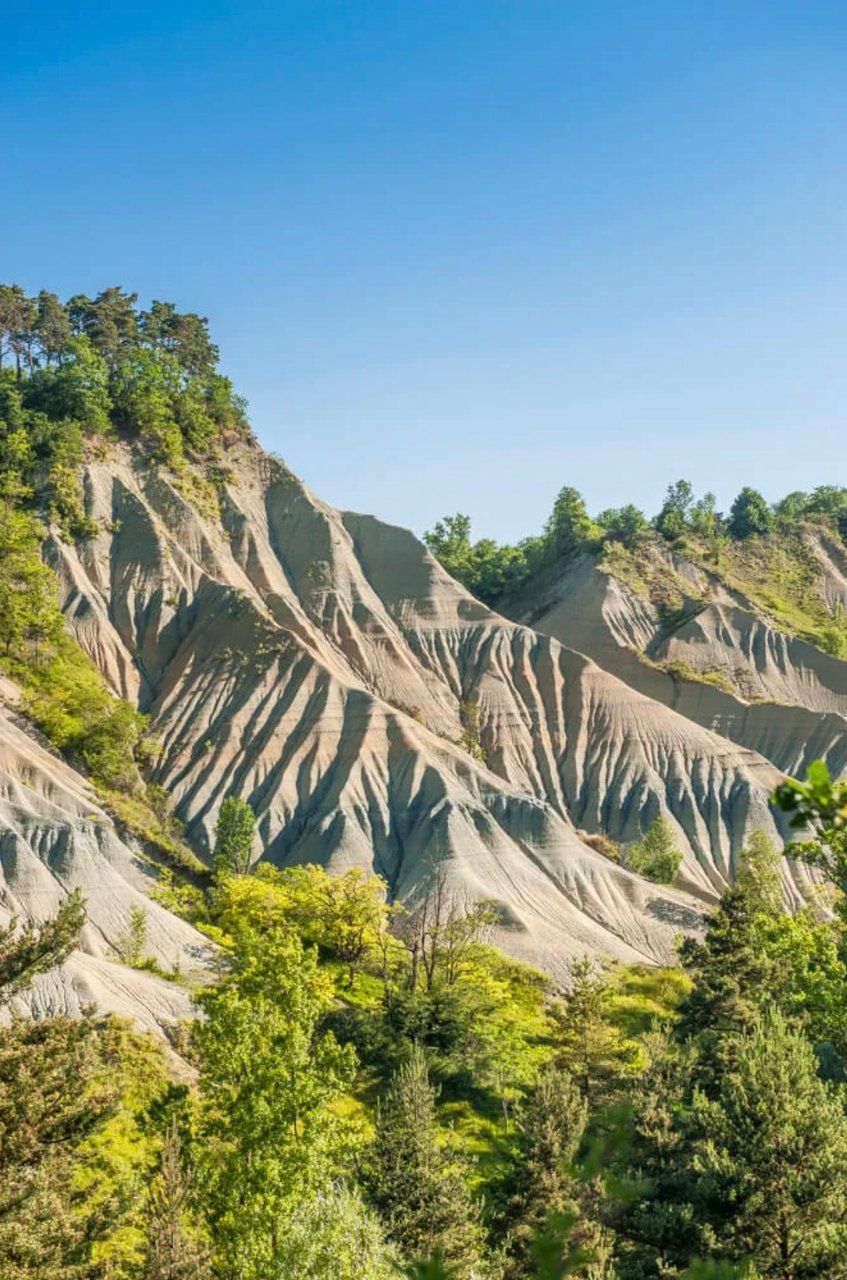 A mountainous landscape with distinct erosion patterns and dense green vegetation.