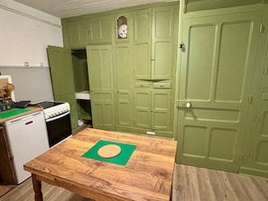 A kitchen with green cabinets, a wooden table, and a clock on the wall. - Chez le Sabotier, central and ideal (Rosières)