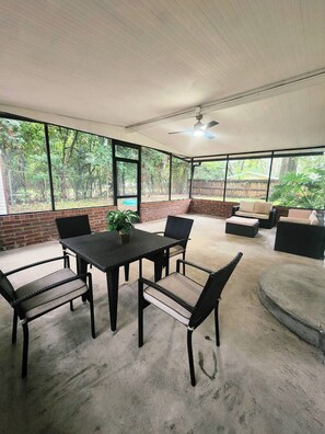 Eine überdachte Terrasse mit Esstisch, Stühlen und einer Sitzecke.