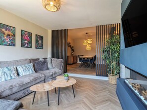 Ein modernes Wohnzimmer mit einer Couch, zwei Couchtischen, einem Fernseher und Kunstwerken an der Wand.