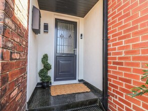 A black door with a glass panel, a small potted plant, and a doormat. - Falcon Luxe (Whitby)