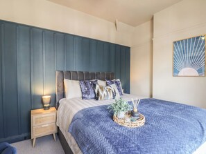 Ein Schlafzimmer mit Bett, Nachttisch, Lampe und Dekoration.