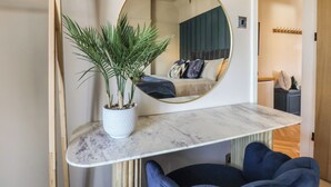 A bedroom with a bed, a round mirror, a potted plant, and a marble shelf. - Falcon Luxe (Whitby)