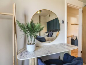 A bedroom with a bed, a round mirror, a potted plant, and a marble shelf. - Falcon Luxe (Whitby)