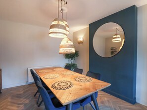 A dining area with a wooden table, blue chairs, and hanging wicker lamps. - Falcon Luxe (Whitby)