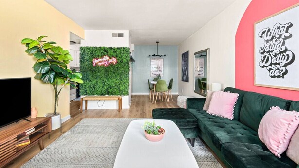 A living room with a green wall, a TV, a sofa, and a coffee table. - The Lyric - Every Stay Hits the Right Note (Nashville)