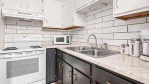 A modern kitchen with white cabinets, a microwave, a stove, a sink, and a coffee maker. - The Lyric - Every Stay Hits the Right Note (Nashville)