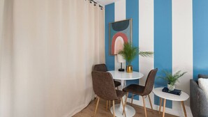 Ein Zimmer mit rautenmusterter Wand, einem runden Tisch mit Stühlen, einer Zimmerpflanze und einem gerahmten Kunstwerk.