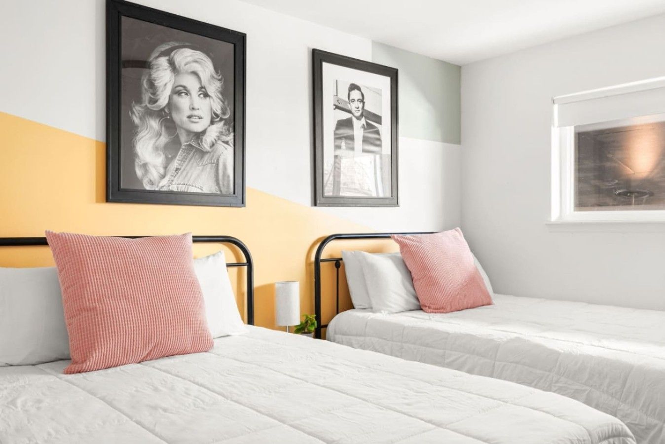 Een hotelkamer met twee bedden, elk voorzien van een kussen en een ingelijste foto aan de muur.