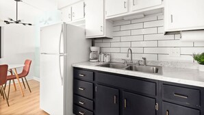 Una cucina moderna con mobili bianchi, basi nere, un lavello doppio e un frigorifero.