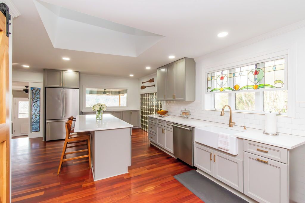 A modern kitchen with a central island, white cabinetry, stainless steel appliances, and a stained glass window.