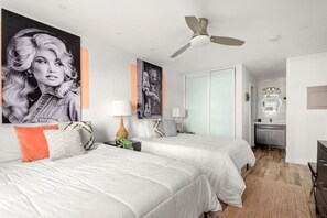 A modern bedroom with two beds, a ceiling fan, and a visible kitchen area. - Best Location! Walk to Midtown Bars (Nashville)