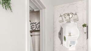 Ein Badezimmer mit weißer Toilette, grauen Schränken und einer Marmor-Spritzschutzwand.