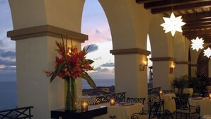 An outdoor dining area with tables set for two, candles, and a vase of flowers. - Pueblo Bonito Sunset Oceanview Junior Suite 🌅 Sleeps 4 | All-Inclusive (Cabo San Lucas)