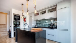 Una cocina moderna con una isla central, electrodomésticos de acero inoxidable y vistas a la ciudad a través del ventanal.
