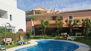 Una piscina con un bordeado de terraza, una banca y una valla.