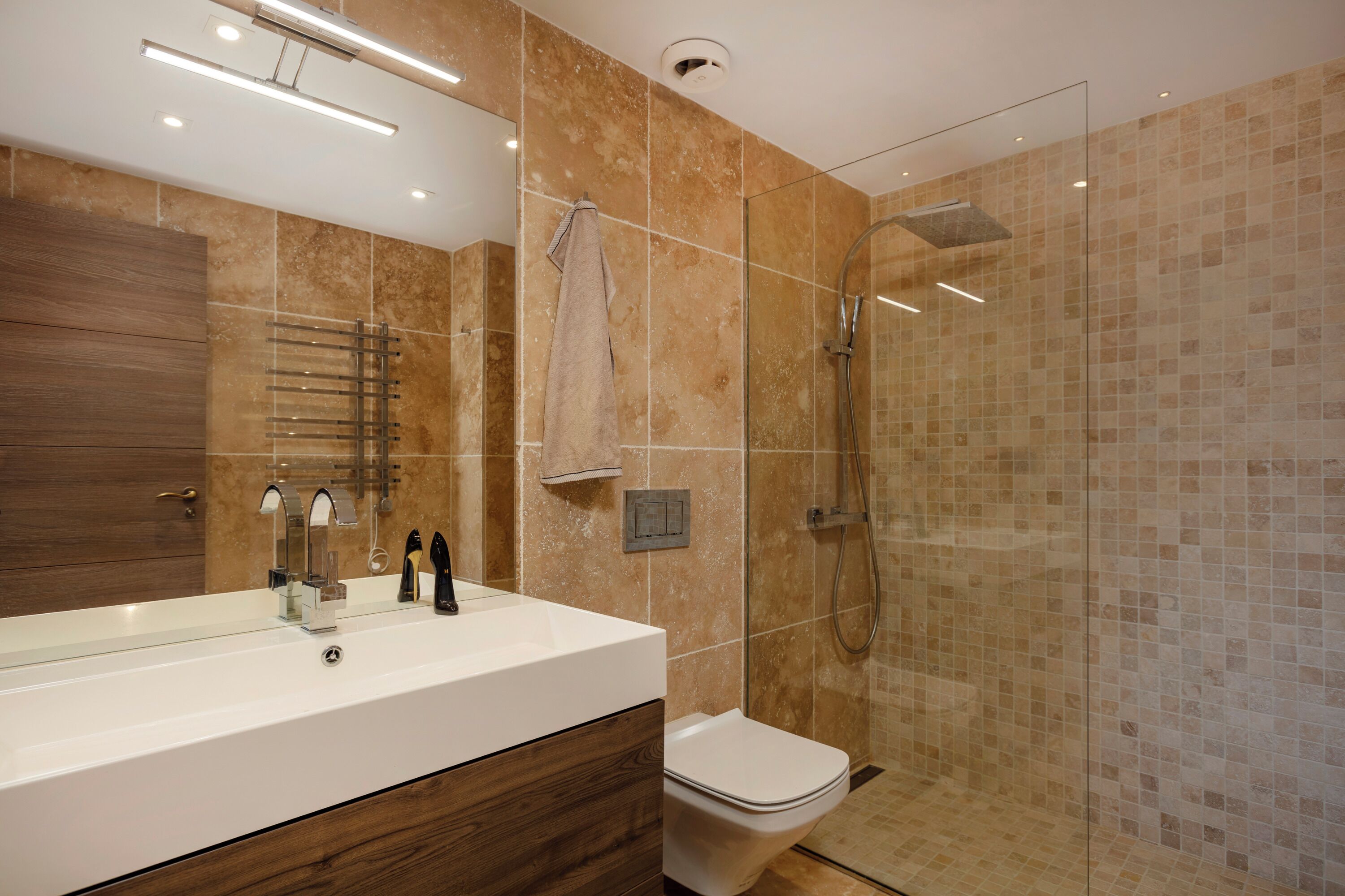 A modern bathroom with a large mirror, a sink, a toilet, and a glass-enclosed shower.