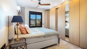 Un dormitorio con una cama, ventilador de techo, ventana y armario.