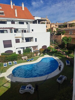 A swimming pool with lounge chairs, a pool maintenance person, and surrounding buildings. - Mza322a - Stylish Penthouse With Large Terrace (Marbella)