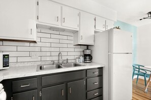 Una cocina moderna con armarios blancos, un lavamanos doble, una cafetera y un refrigerador.