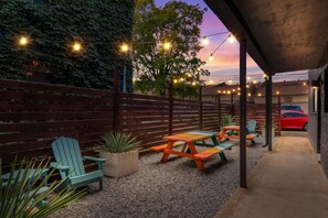 An outdoor patio area with wooden benches and chairs, string lights, and a gravel ground. - The Lyric - Wake Up in the Heart of Nashville (Nashville)