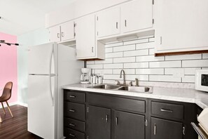 A modern kitchen with white cabinets, a stainless steel sink, and a refrigerator. - The Lyric - Wake Up in the Heart of Nashville (Nashville)
