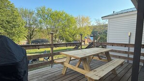 Une terrasse en bois avec une table de pique-nique, un barbecue et un espace abrité.