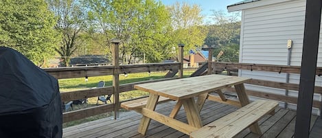 A wooden deck with a picnic table, a grill, and a covered area.