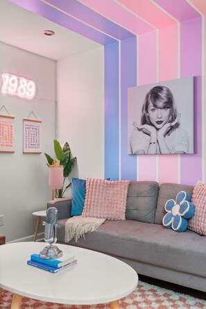 Ein modernes Wohnzimmer mit einem grauen Sofa, einem runden weißen Couchtisch und einem großen gerahmten Bild an der Wand.