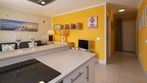 Une cuisine moderne dotée d’un îlot central, d’un coin repas avec un canapé et d’un couloir menant à une porte.