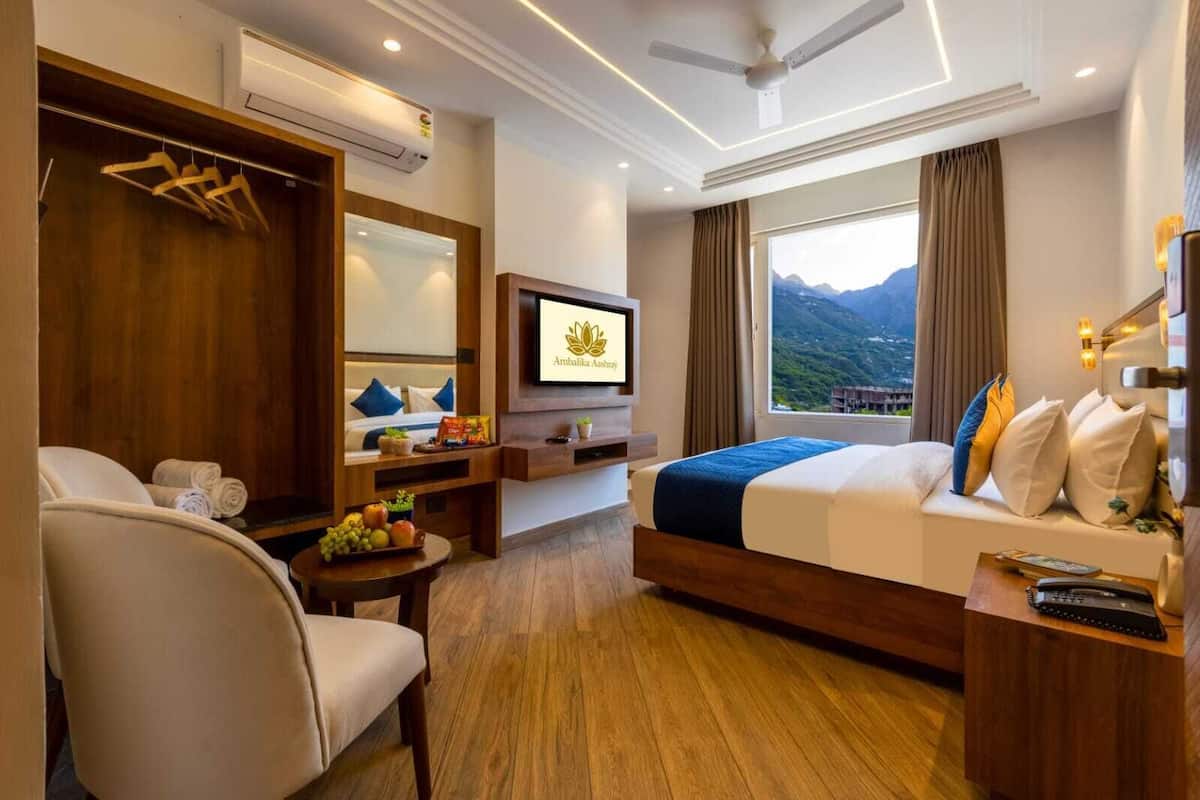Habitación de hotel con cama, escritorio, silla, televisión y ventana con vista a la montaña.