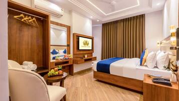 Habitación de hotel con cama, escritorio, silla, televisor, armario y aire acondicionado.