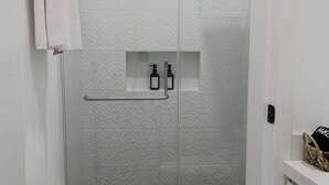 Et badeværelse med bruser, toilet og håndklædestige.