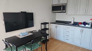Een kleine keuken met een flatscreen-tv, een magnetron en een spoelbak.