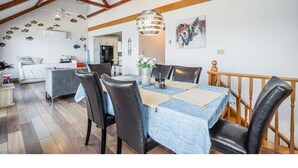 Un comedor con techo de madera, una mesa con sillas y una pared decorada con un vinilo de pez.