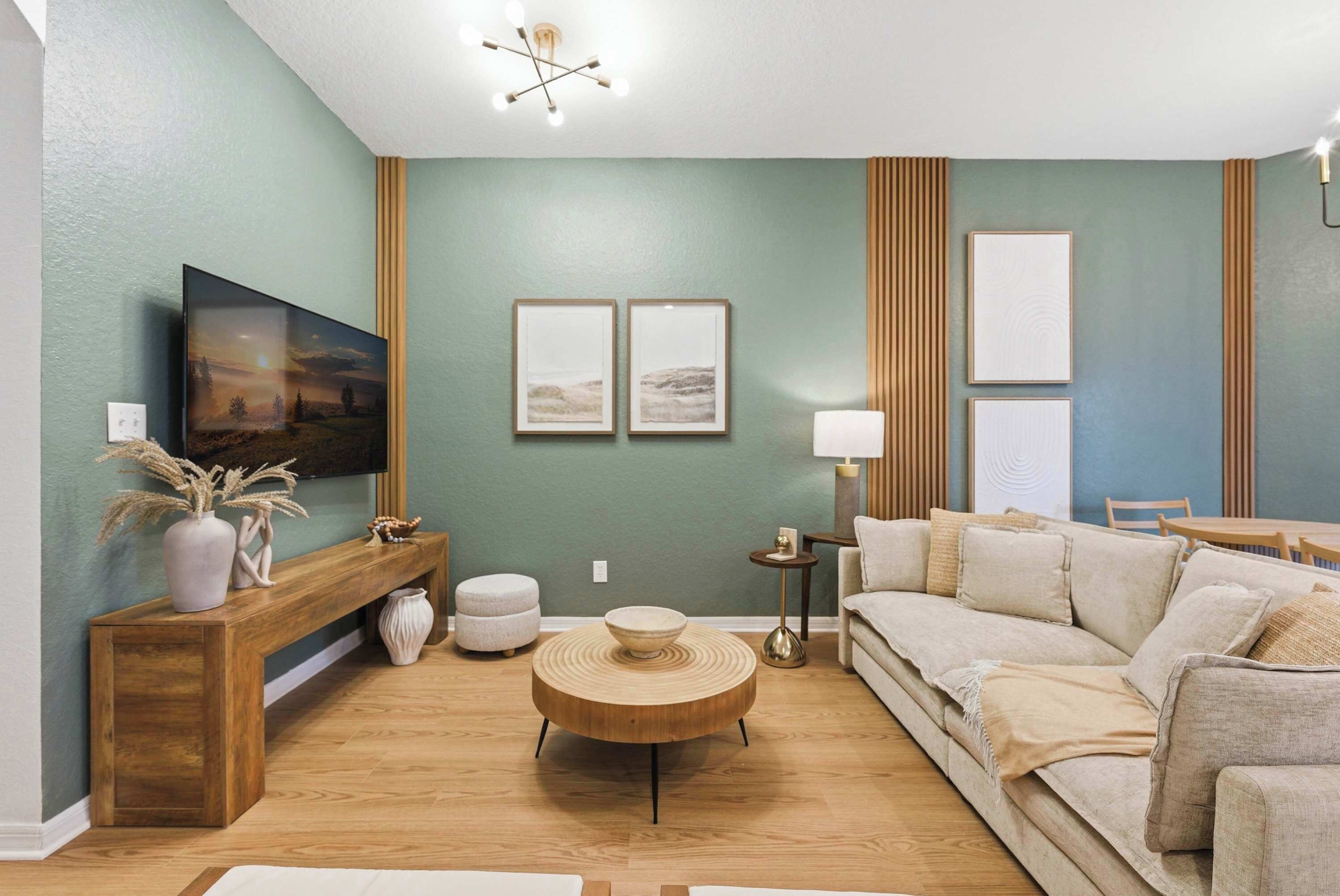 Ein Wohnzimmer mit einer hölzernen Bank, einem runden Couchtisch, einer Couch und gerahmten Bildern an der Wand.