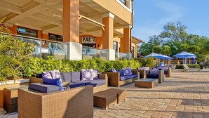 An outdoor seating area with wicker furniture and cushions, a Clubhouse sign, and a ZAC'S Sports Bar sign. - Private Jacuzzi, 15 Min to Disney! Modern 4BR Home (Kissimmee)
