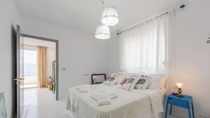 Ein Schlafzimmer mit Bett, Nachttisch und Meerblick.
