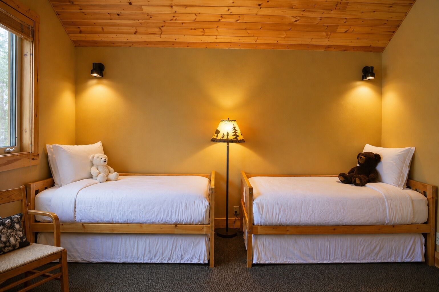 A room with two wooden bunk beds, a bedside lamp, and a window.
