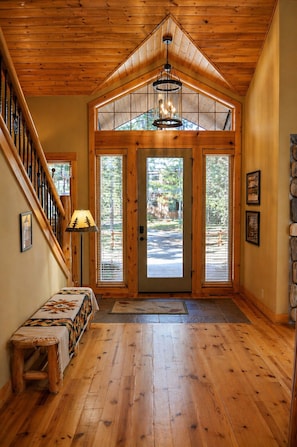A wooden interior with a staircase, a bench, a door with glass panels, and a chandelier. - Black Butte Ranch South Meadow 145 (Black Butte Ranch)