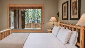 Een slaapkamer met een groot raam, een houten hoofdbord en een bed met witte lakens.