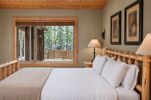 A bedroom with a large window, wooden headboard, and a bed with white linens. - Black Butte Ranch South Meadow 145 (Black Butte Ranch)
