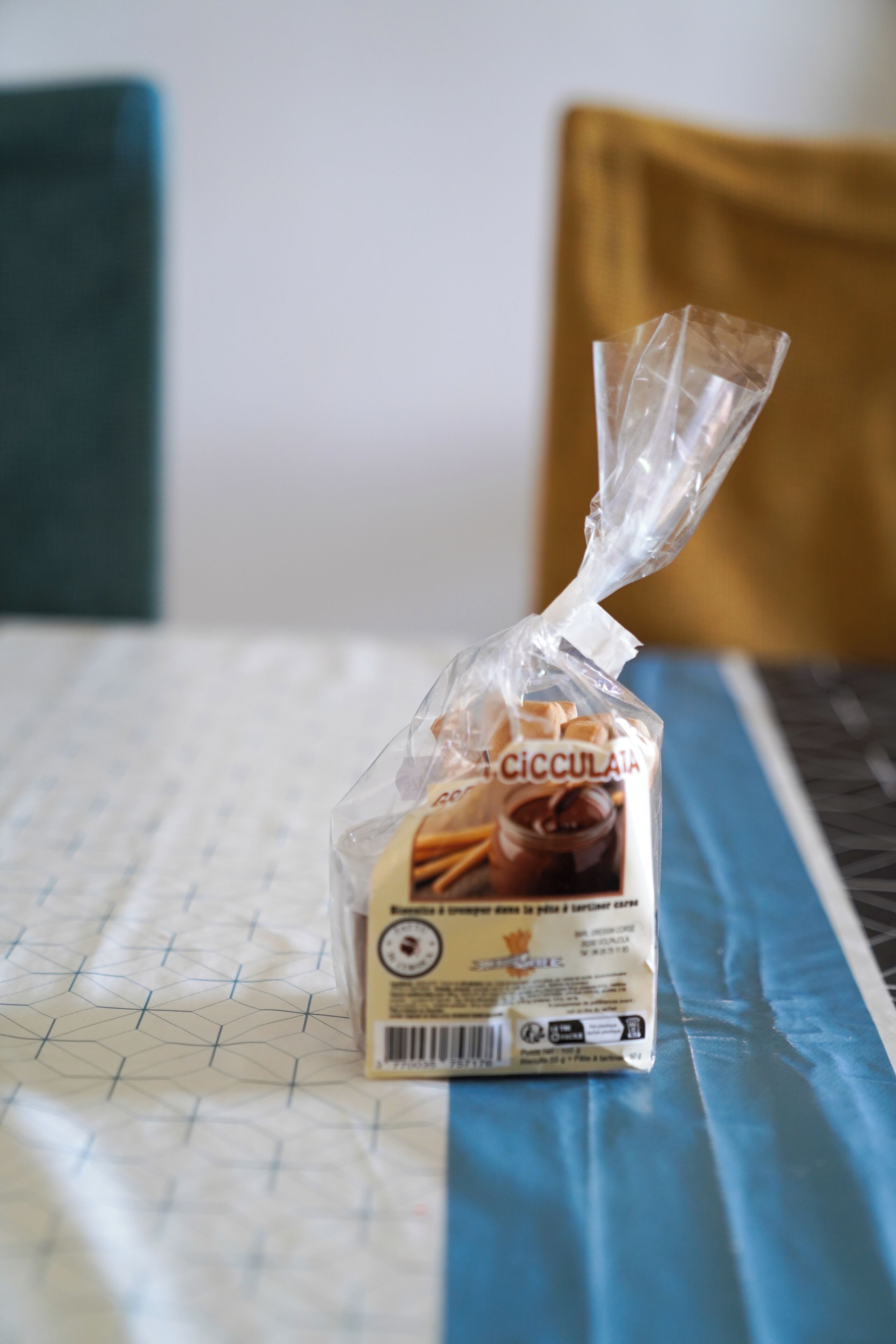 Un alimento envasado sobre una mesa con mantel de estampado geométrico.