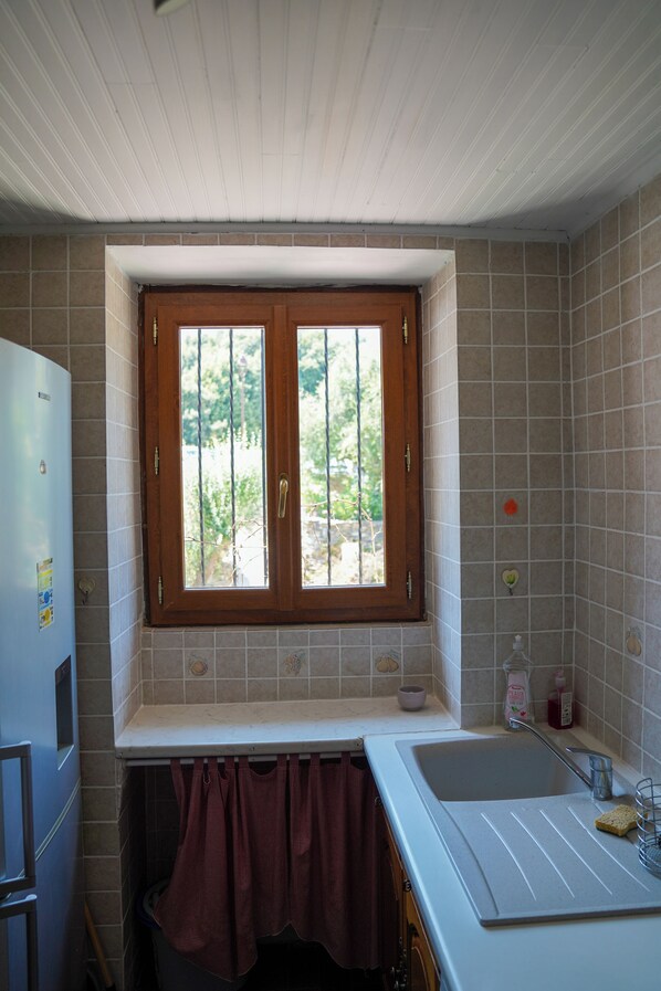 A kitchen with a window, sink, and a refrigerator.